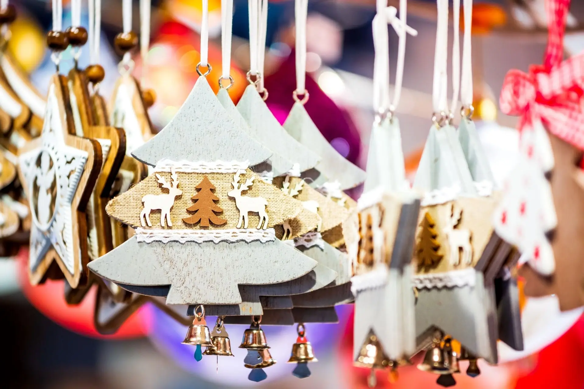 Handmade wooden Christmas tree ornaments hanging at a holiday market display.