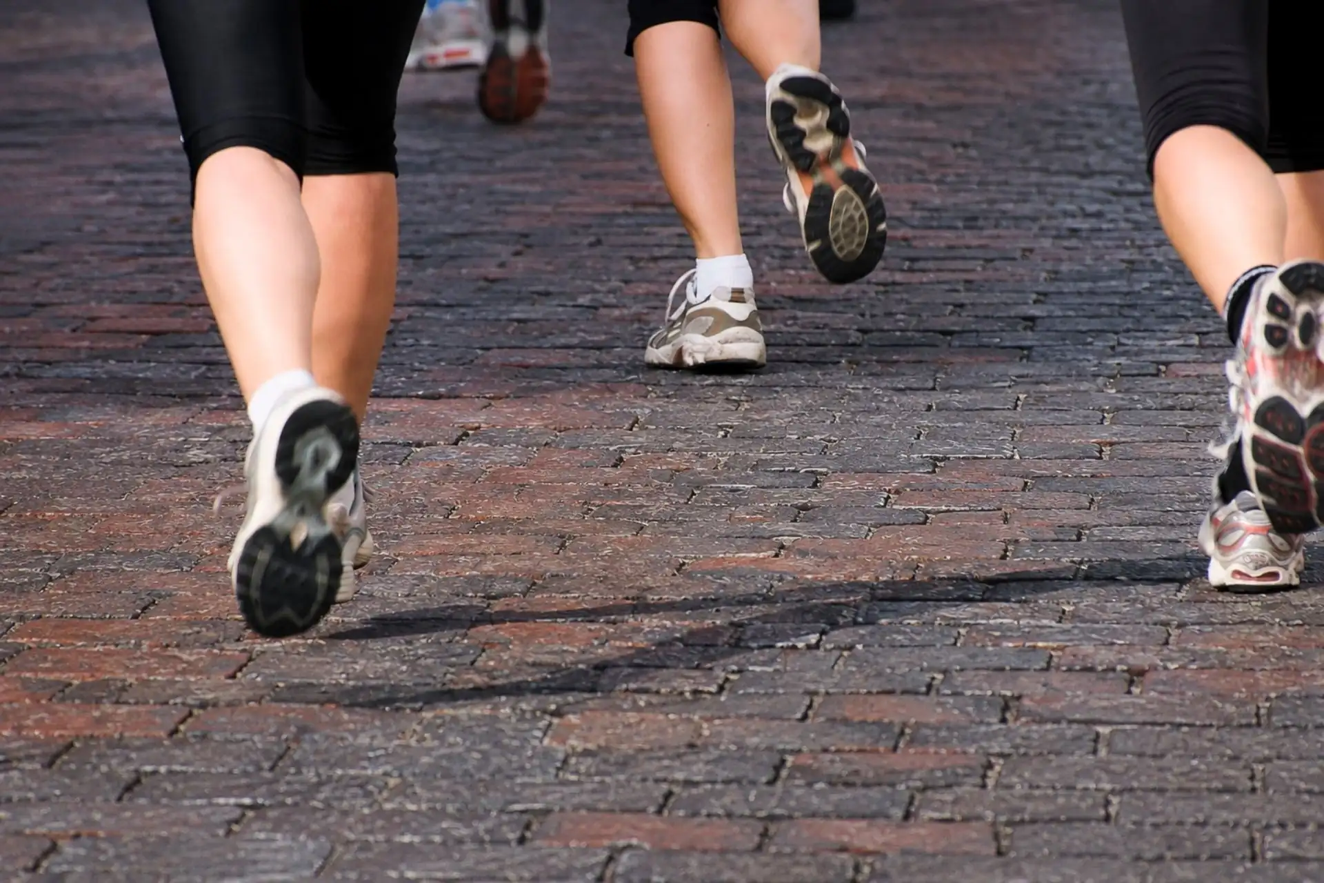 Close-up view of runners' legs and running shoes on the historic brick-paved street during the Hit the Bricks 5K in Zionsville, Indiana.