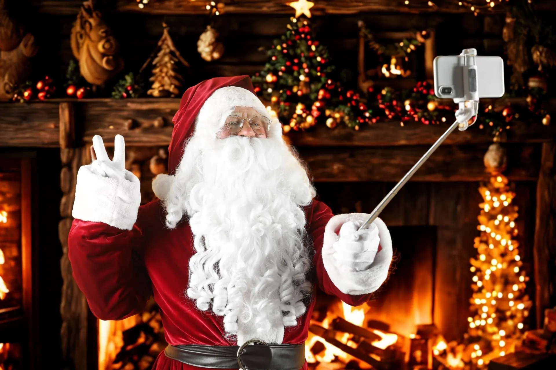 Santa Claus using a selfie stick in front of a Christmas tree, a festive stock photo announcing the Zionsville Selfies with Santa event schedule.