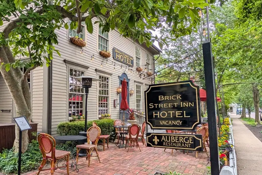Outdoor brick patio seating and entrance sign for Auberge Restaurant and Brick Street Inn on Main Street in Zionsville, Indiana.