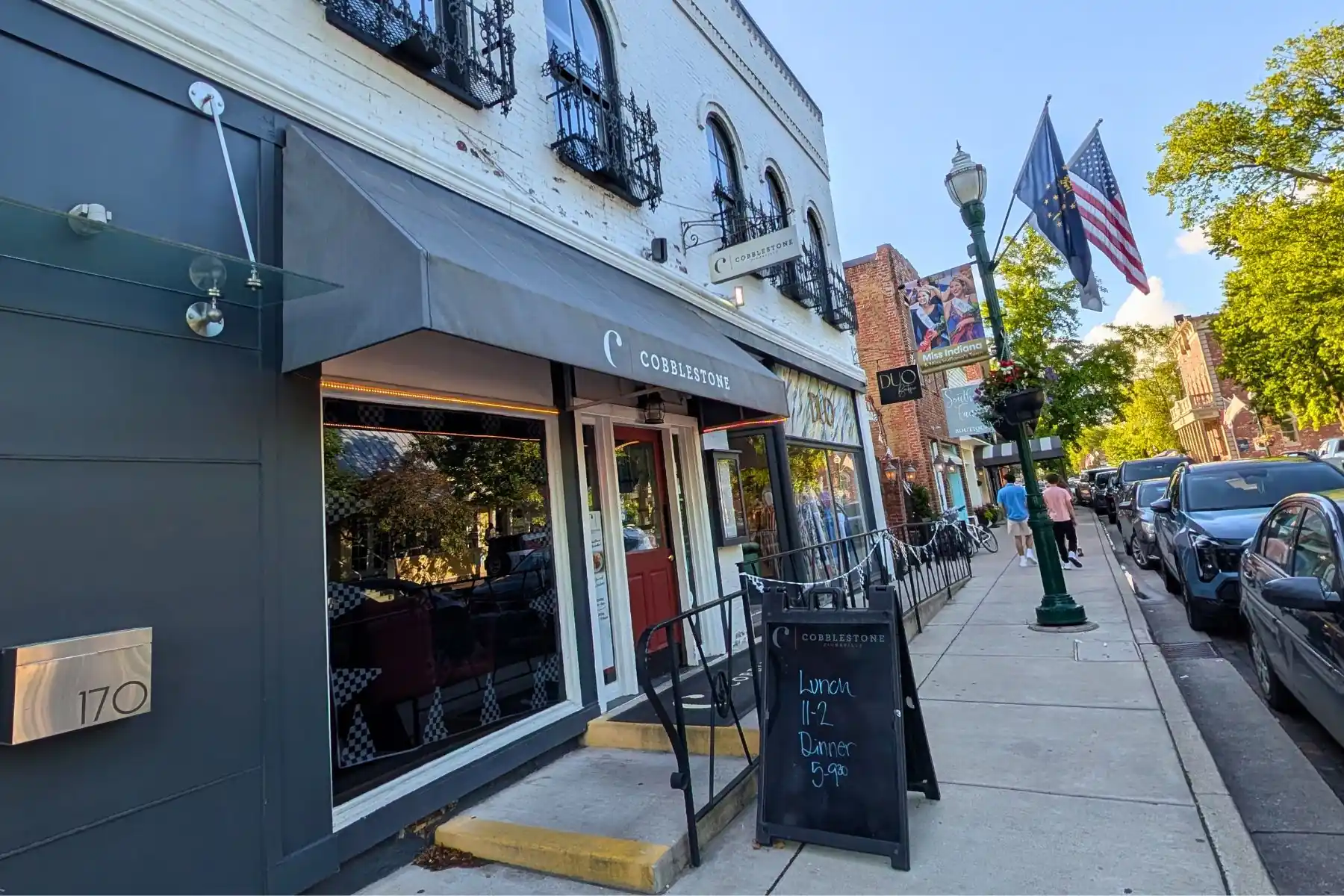 Exterior storefront and sidewalk sign for Cobblestone restaurant on Main Street in downtown Zionsville, Indiana.