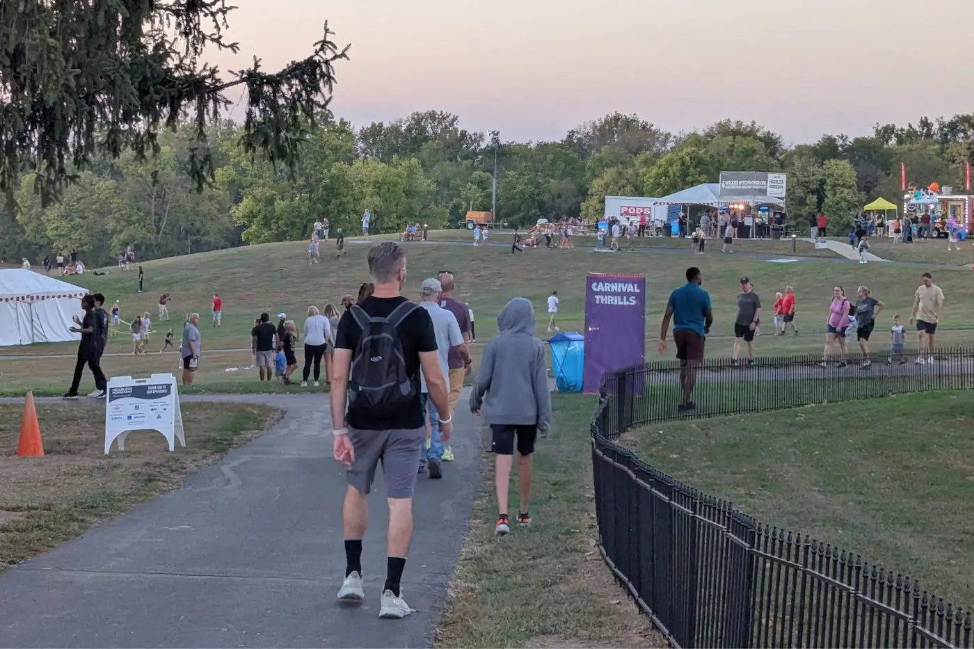 Festival visitors walking along paved paths across the outdoor grounds at Conner Prairie in Fishers, Indiana.