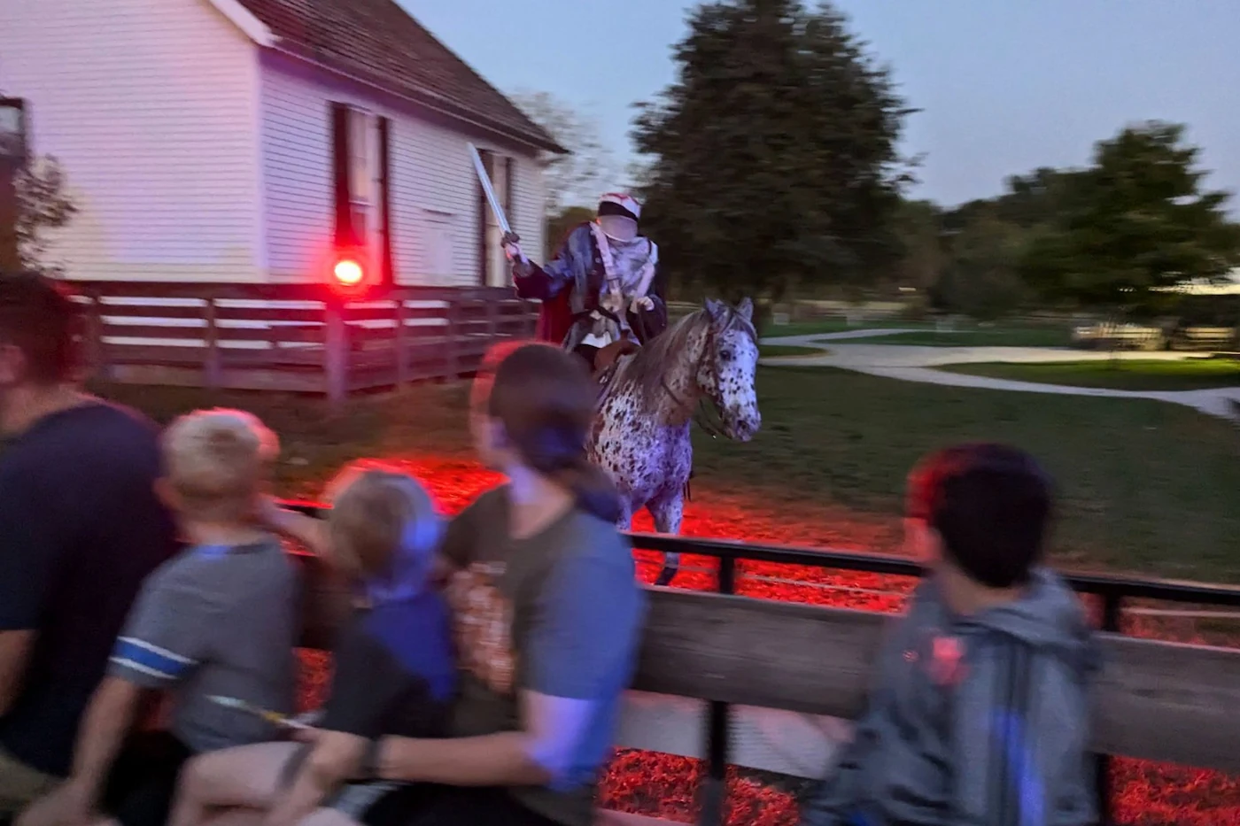 The Headless Horseman on a spotted horse illuminated by red light beside a hayride wagon at Conner Prairie in Fishers, Indiana.