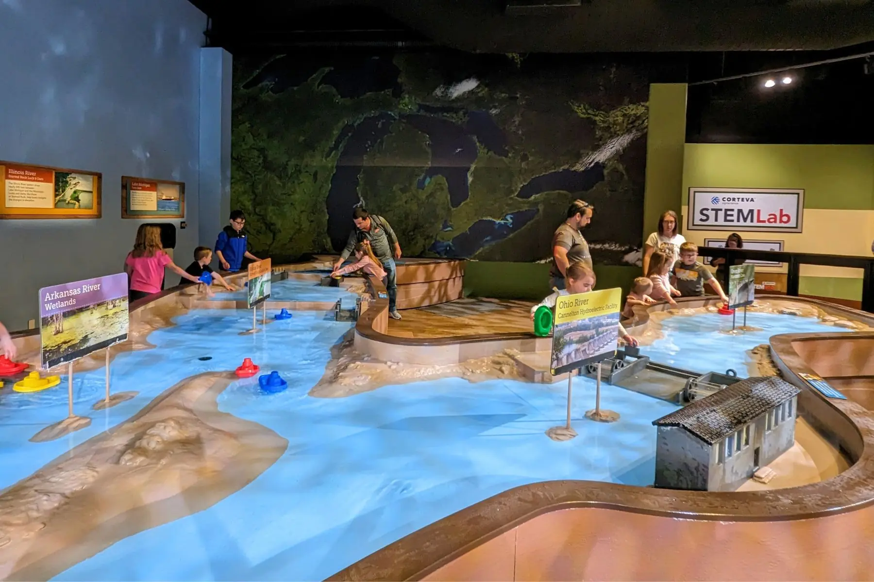 The water play table and STEM exhibit at The Children’s Museum of Indianapolis featuring toy boats, dams, and interactive river channels.