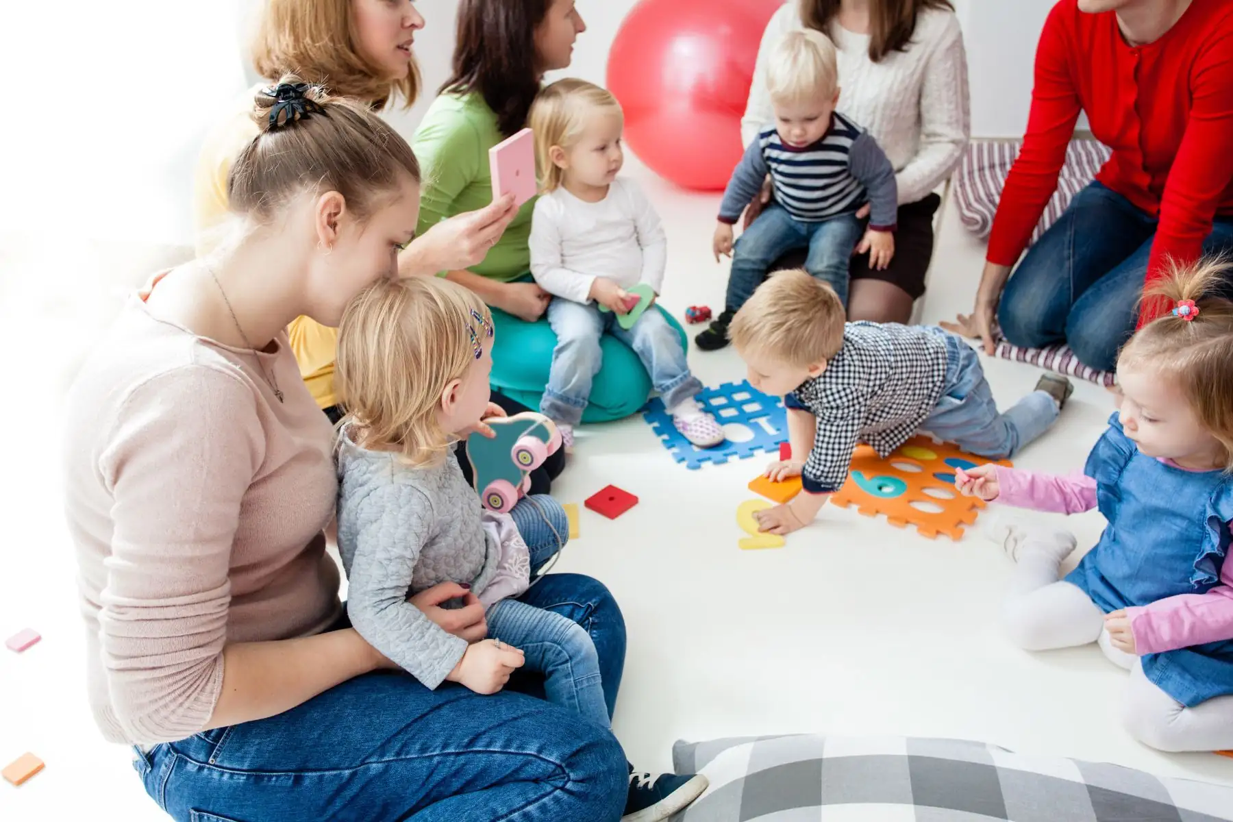 Parents and toddlers participating in a parent-and-child class with colorful toys and hands-on learning activities.