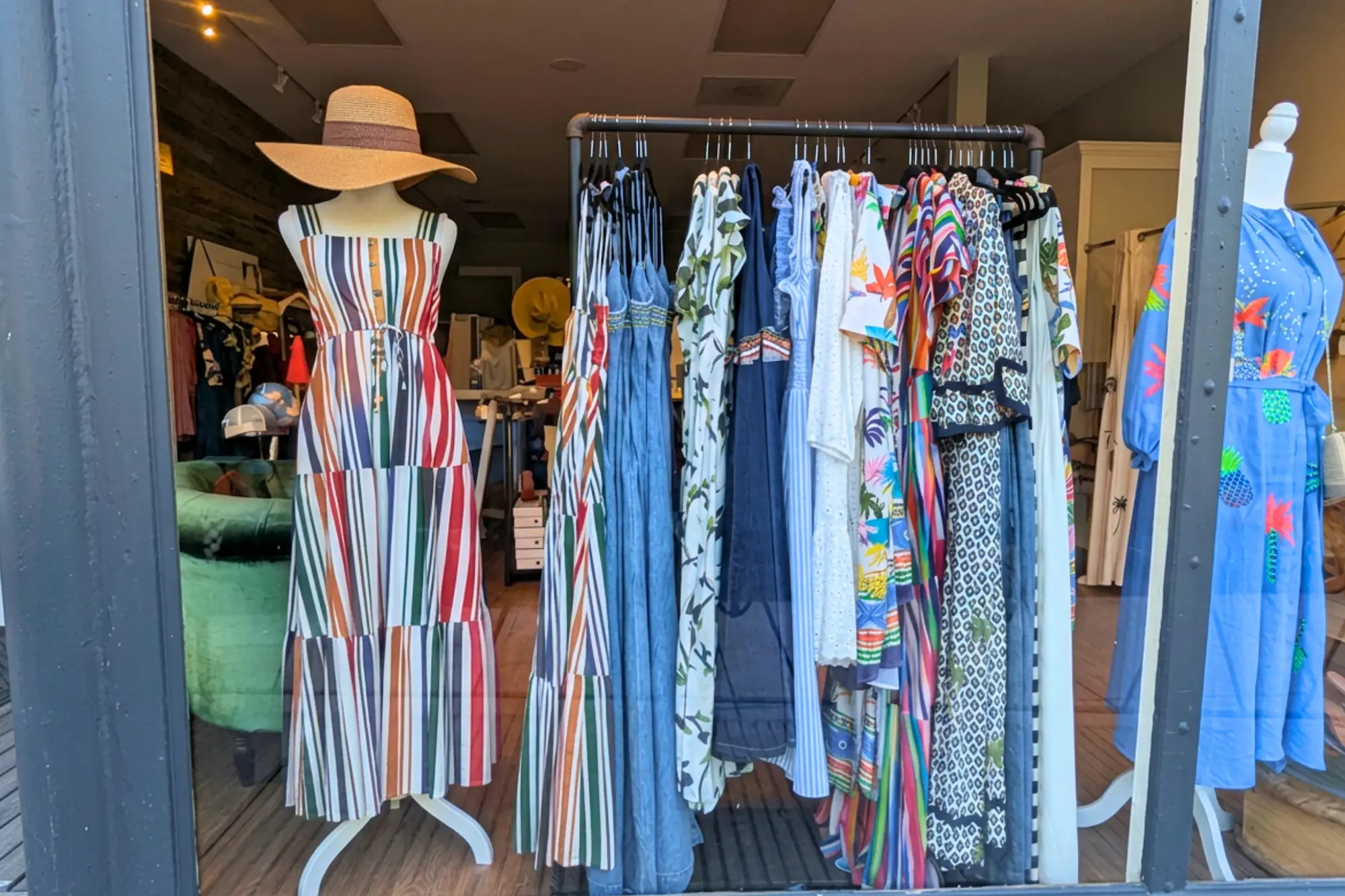 A front window display at Duo Boutique in downtown Zionsville showing mannequins and a clothing rack with patterned women's sundresses.