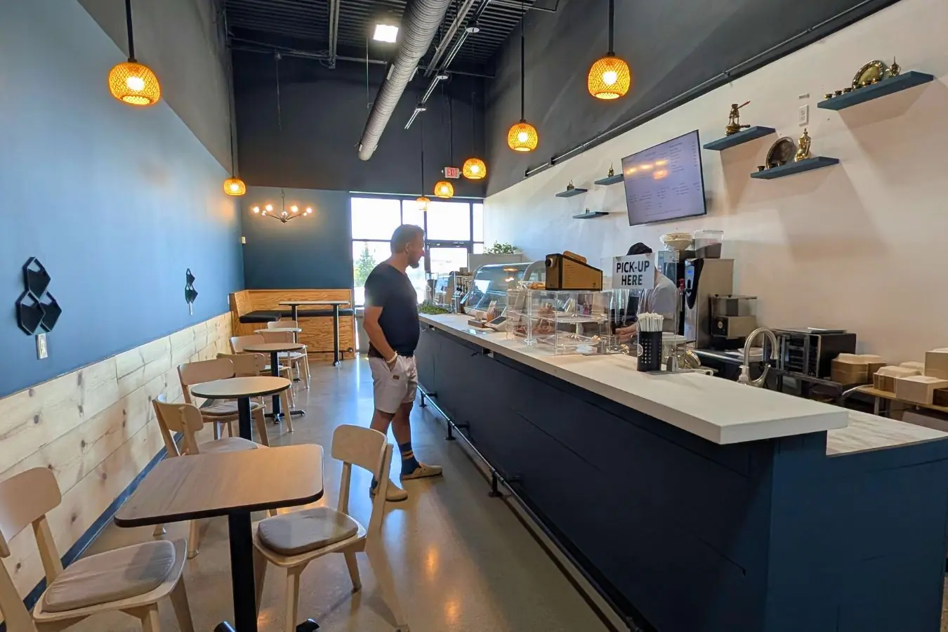 Mochaland coffee shop in Zionsville, showing a narrow modern café interior with dark walls, light wood seating, pendant lights, a long counter, and display shelves.