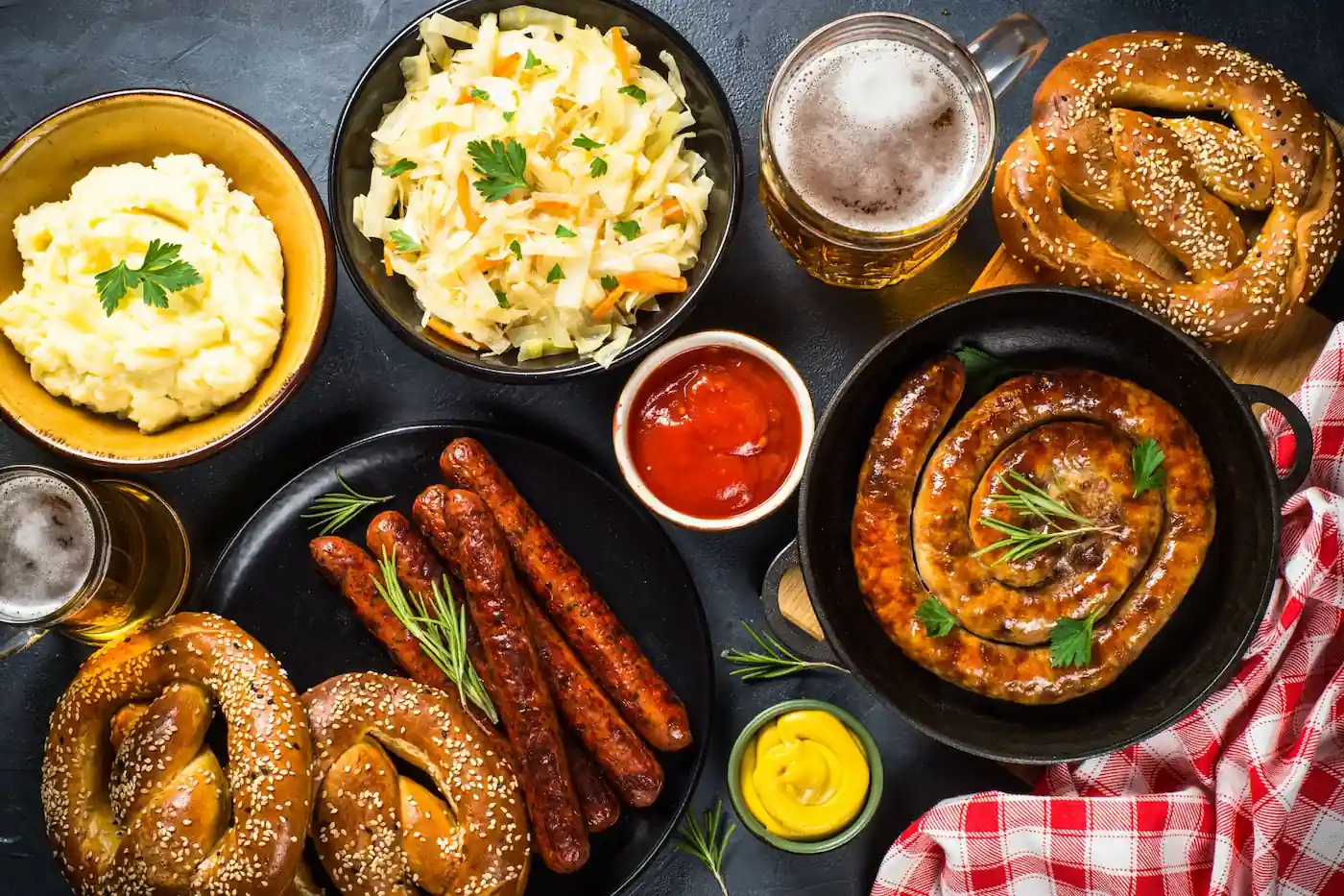 Oktoberfest food spread with German sausages, soft pretzels, cabbage, potatoes, mustard and mugs of beer