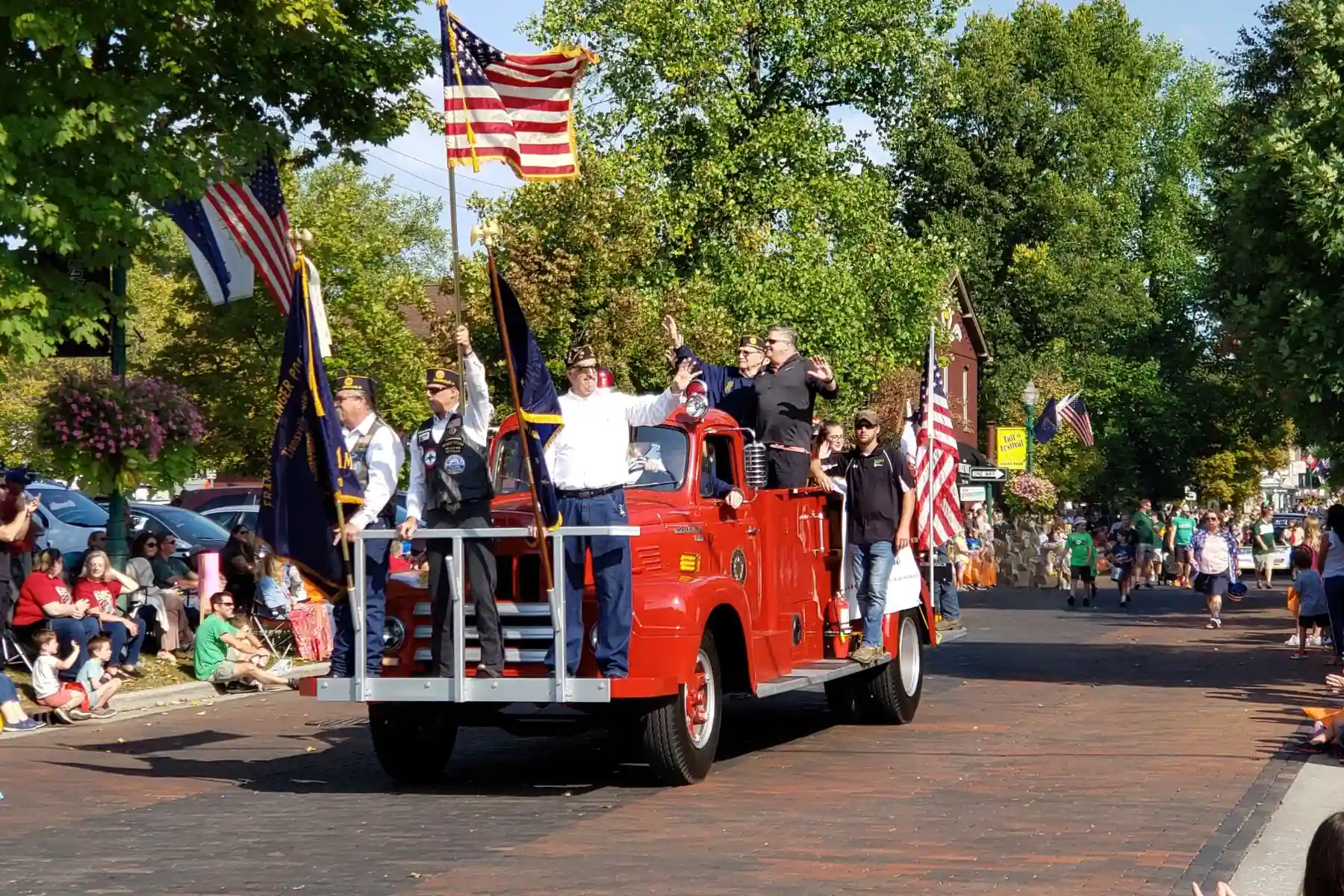 Veterans carrying American flags while riding on a vintage red fire truck during the Zionsville Fall Festival parade down Main Street.