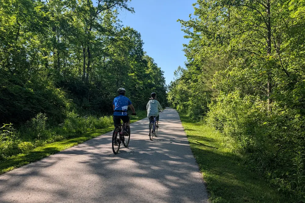 Two cyclists riding on the paved Big-4 Rail Trail near the perimeter of Mulberry Fields Park in Zionsville.